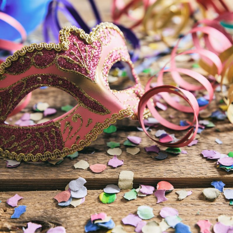 Carnival party. Mask, confetti and serpentines on wooden background